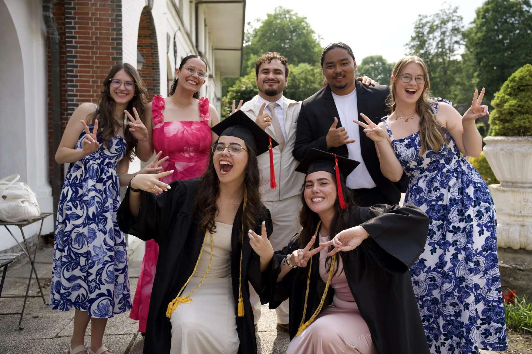 Graduates and friends celebrating with peace signs