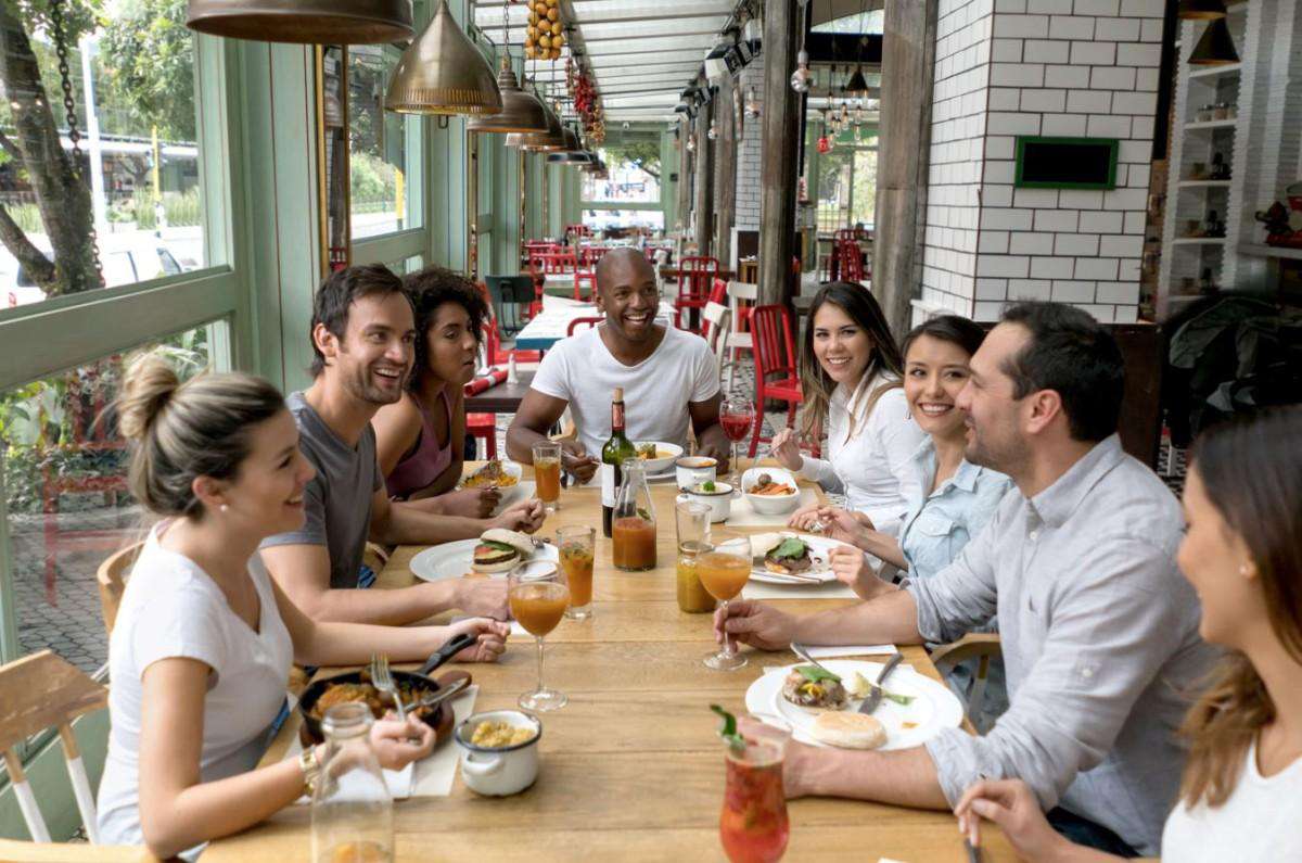 A long table of friends sharing lunch at a restaurant