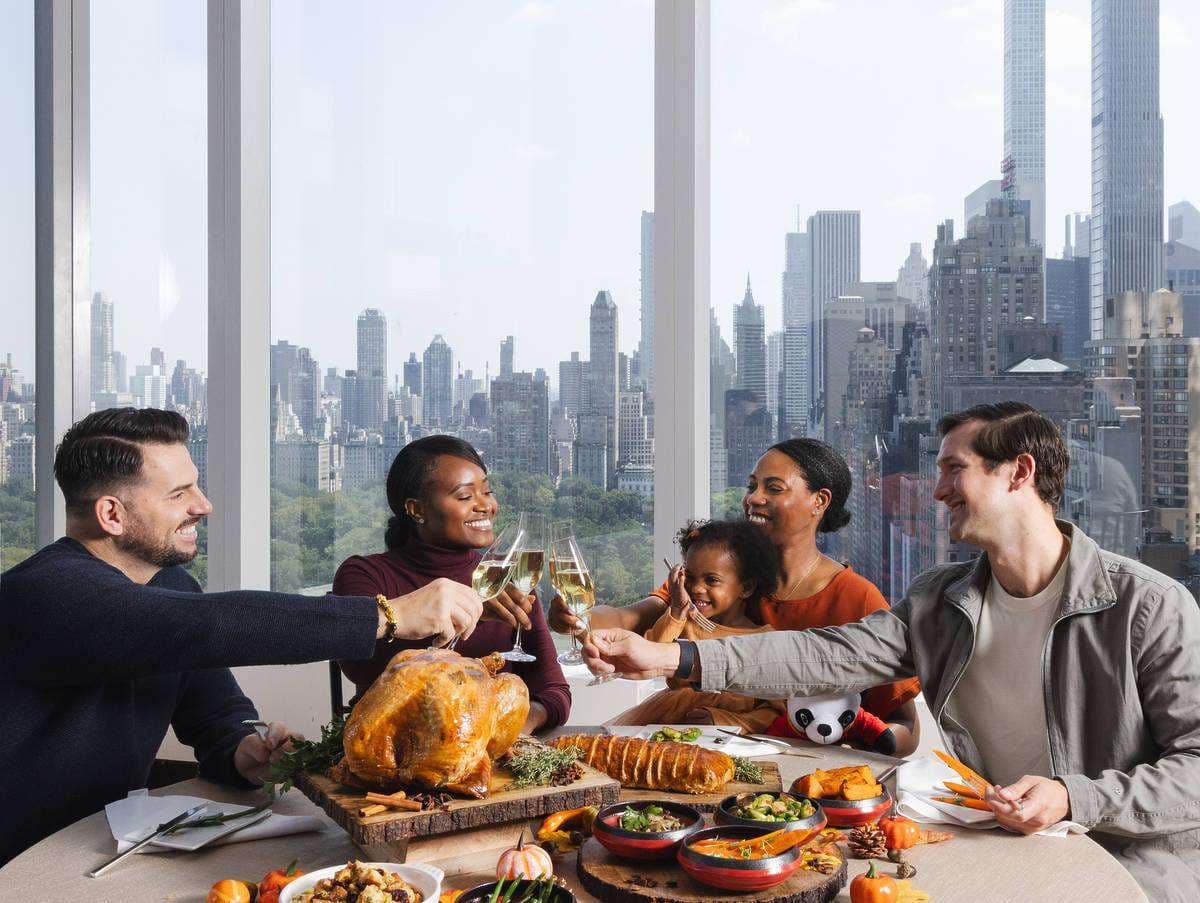 A family toasting at a dinner table above the city skyline