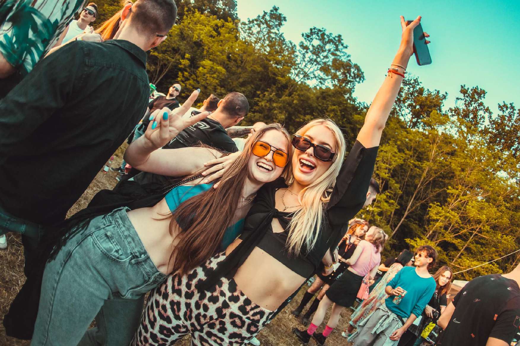 Two friends laughing in the crowd at an outdoor festival